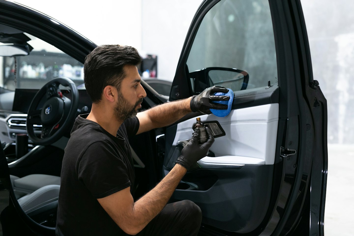 Un detailer professionista applica il rivestimento al pannello di una portiera d'auto.