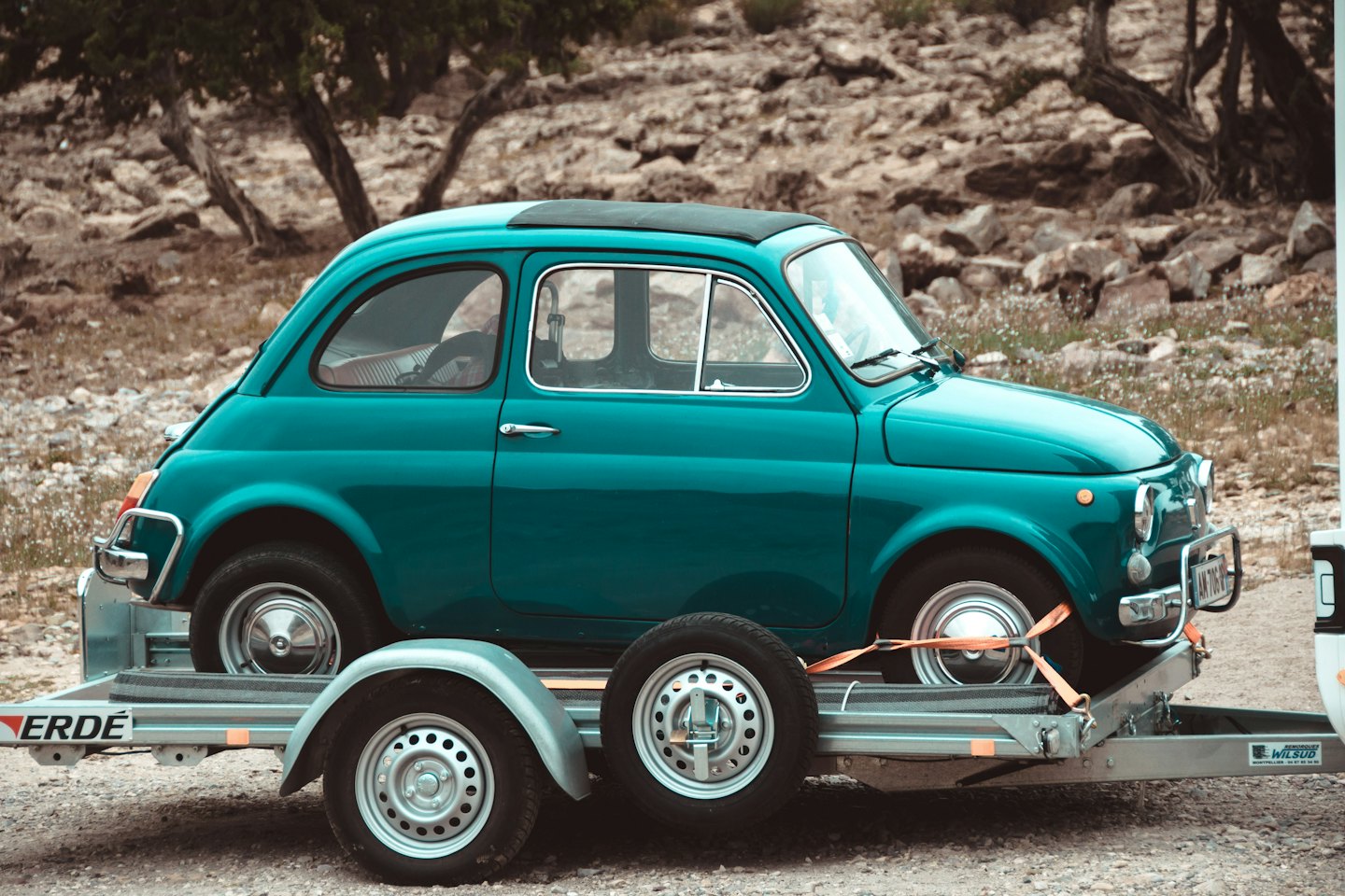Trasporto Veicoli Fiat 500 d'epoca color verde acqua assicurata su un carrello per auto.