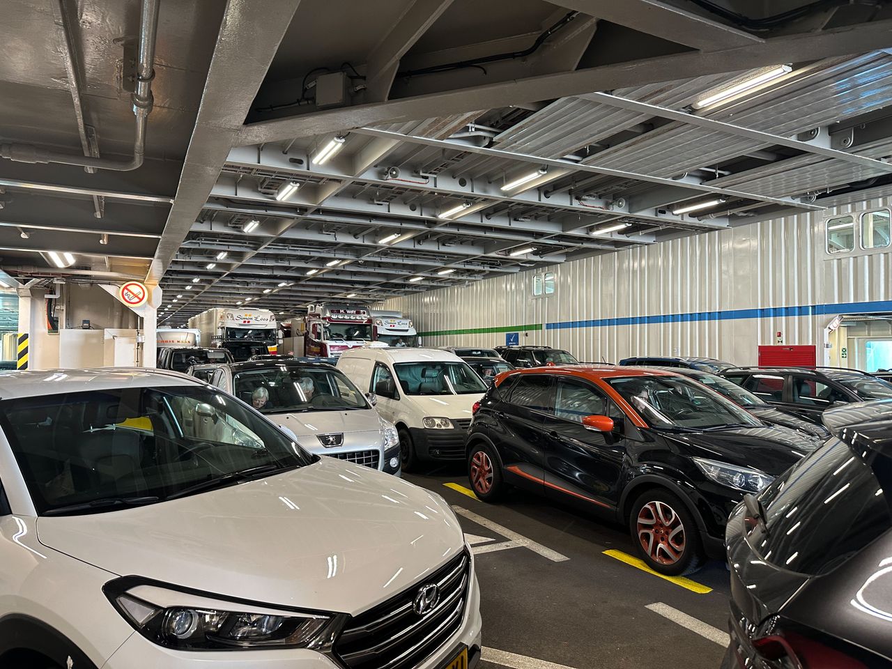 Cars and trucks parked closely together on a ferry deck, emphasizing transportation and travel.