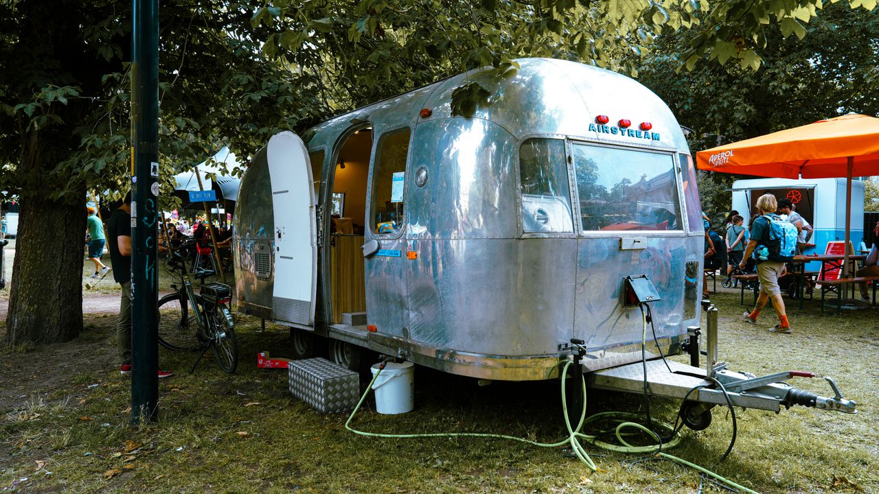 The Art of Drawing Readers In: Your attractive post title goes here Classic Airstream trailer parked outdoors during a lively festival event.